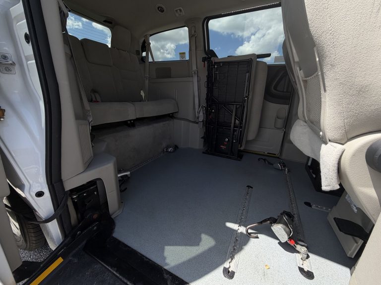 Lowered floor wheelchair position inside the van seen from the open side door, with rear bench seat and floor securement straps