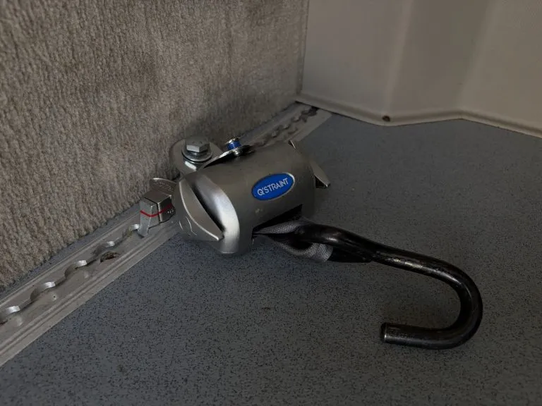 Retractable wheelchair tie-down anchor mounted in the floor track