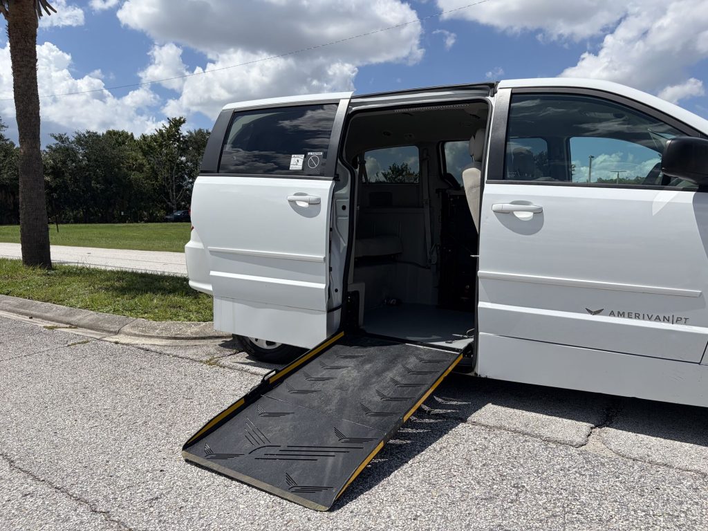 Manual fold-out side entry ramp lowered to the ground from the passenger side sliding door, showing the ramp incline and width